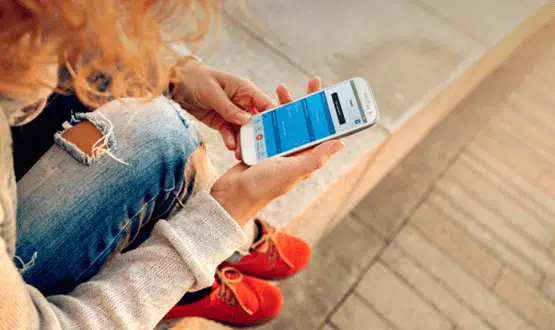 A young woman looking at a text reminder on her mobile phone