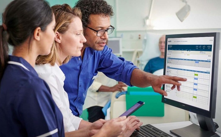 Three clinicians looking at computer screen