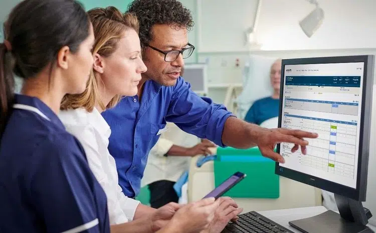 Three clinicians looking at computer screen