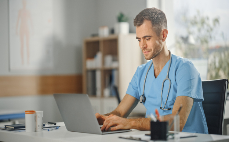 Male doctor typing at laptop