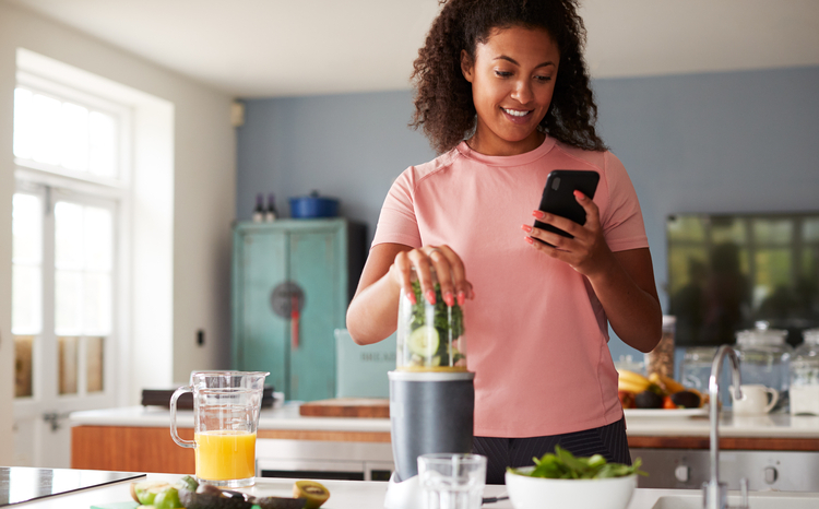 Woman Using Fitness Tracker To Count Calories For Post Workout Juice Drink SHe Is Making