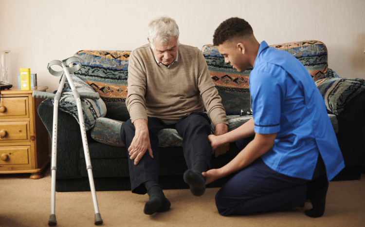 A carer helping an older man to stand up