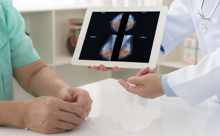 Doctor explaining mammogram results of breast test from x-ray scan on digital tablet screen to patient