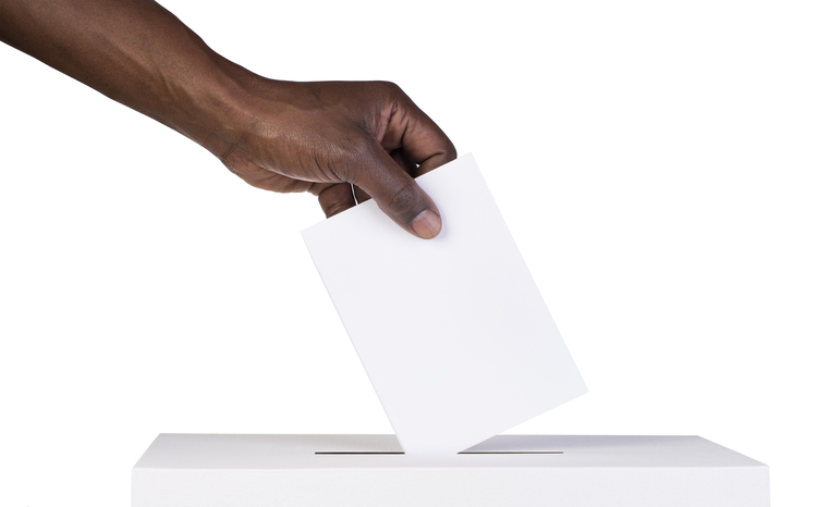 Hand placing a vote into ballot box