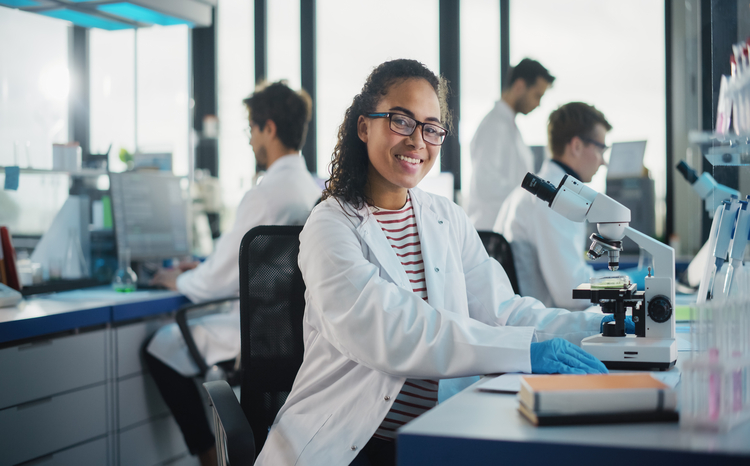 Woman in lab coat looking in microscope